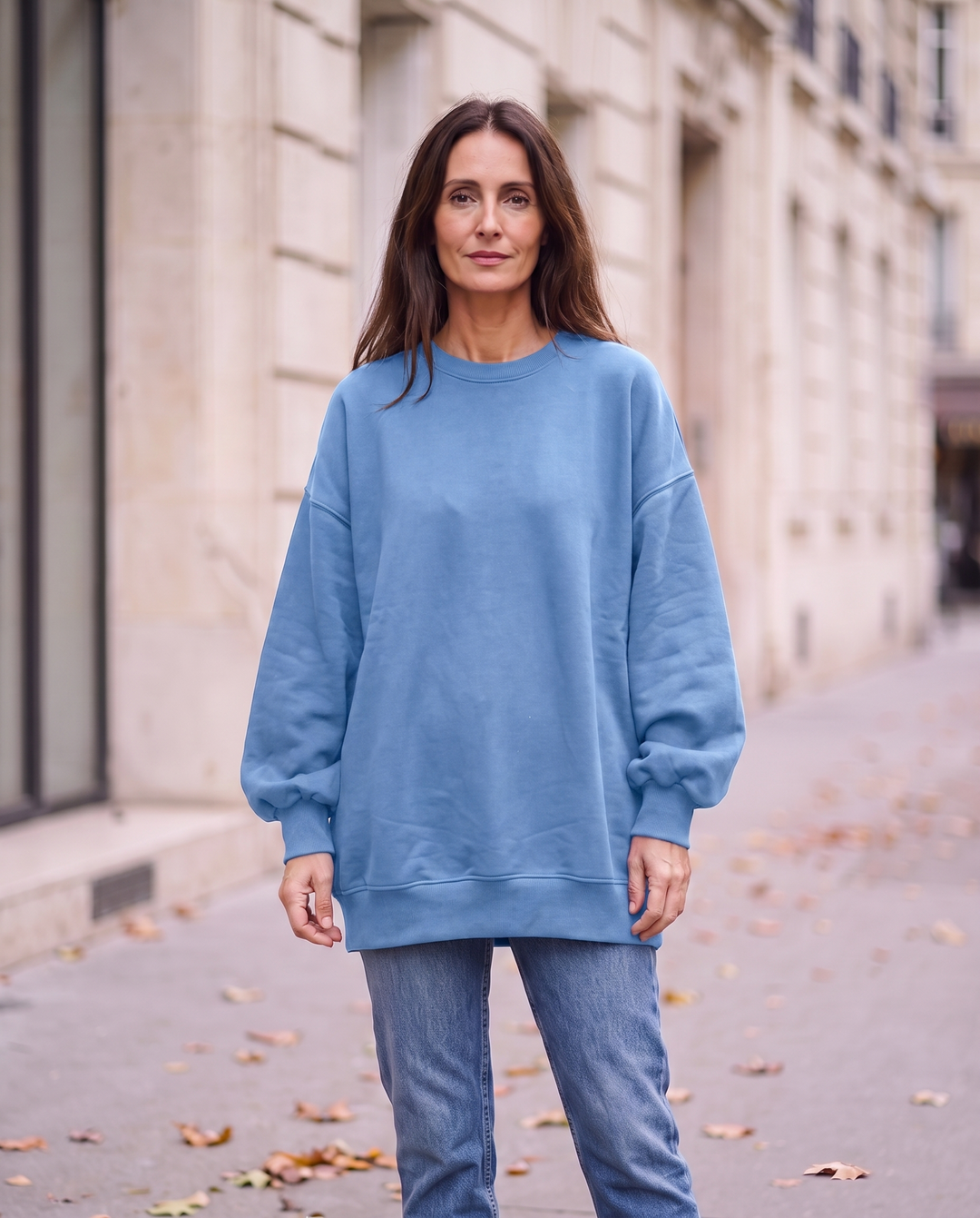 Kvinna i blå oversized sweatshirt utan sidöppningar, framifrån