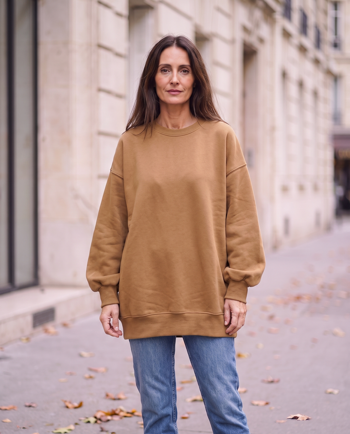 Kvinna i kamelbrun oversized sweatshirt utan sidöppningar, framifrån