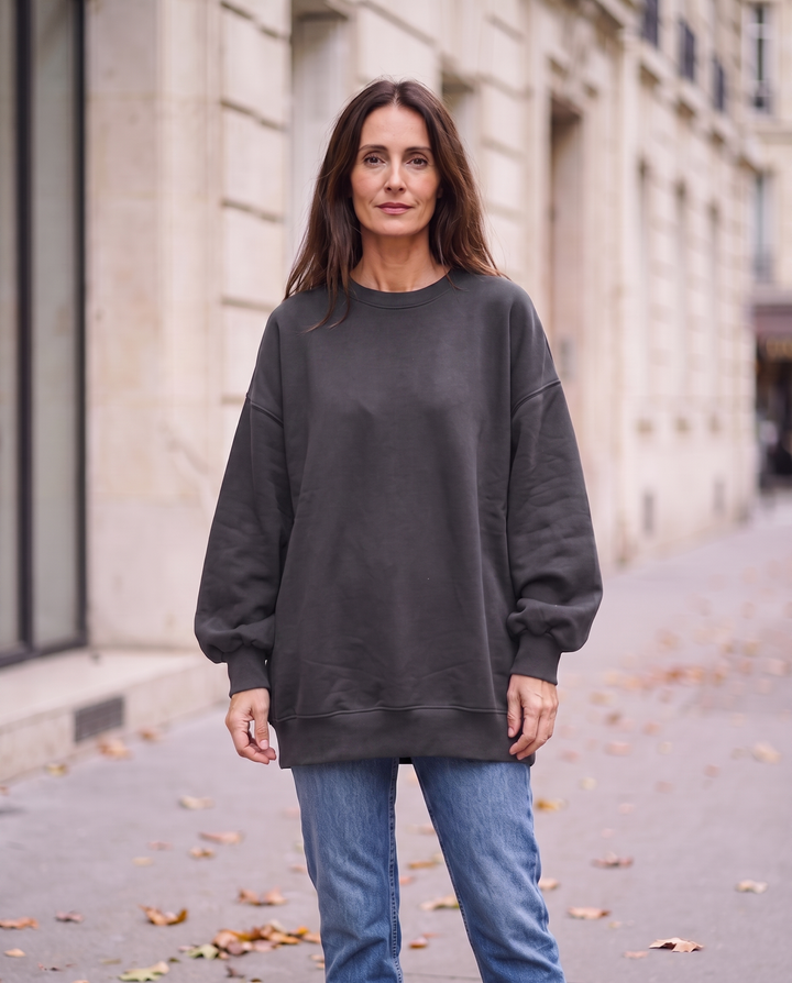 Kvinna i grå oversized sweatshirt utan sidöppningar, framifrån