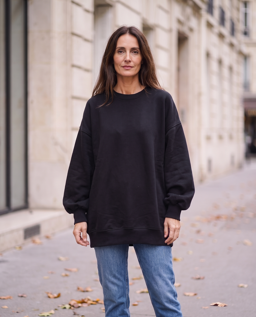Kvinna i svart oversized sweatshirt utan sidöppningar, framifrån