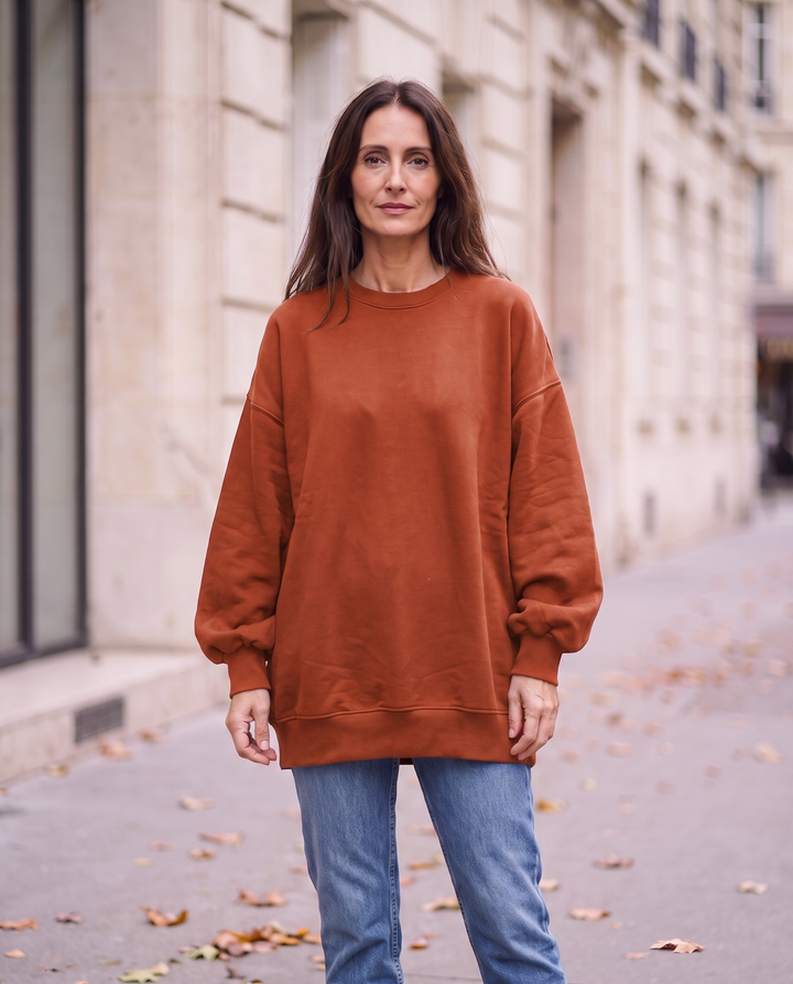 Kvinna i roströd oversized sweatshirt utan sidöppningar, framifrån