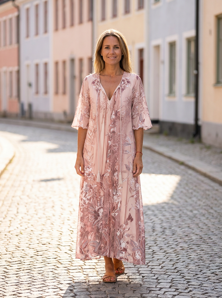 Sophie blommig maxiklänning i puderrosa med halvlånga vida ärmar, buren på solig kullerstensgata i gammal svensk stadskärna – lissendra.com